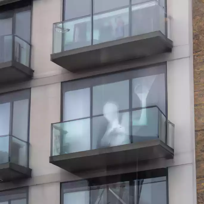 Image of a blurry, humanoid ghost in the window of a modern apartment building.